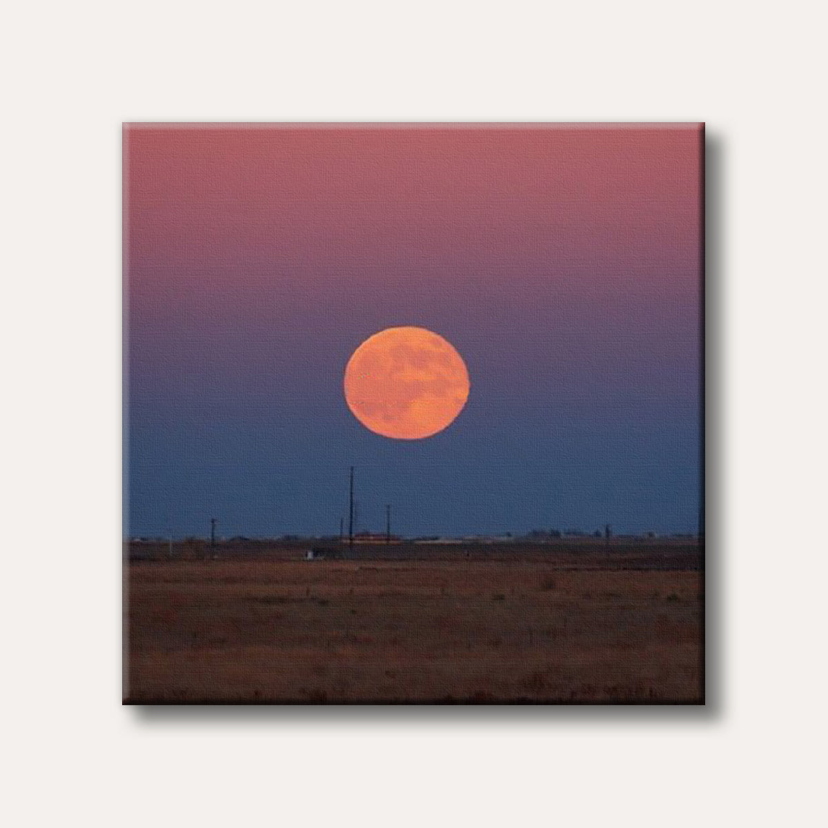 A large, glowing orange full moon setting over a wide, desolate landscape with power lines, under a sky transitioning from deep blue to soft pink, captured in a realistic photographic style.