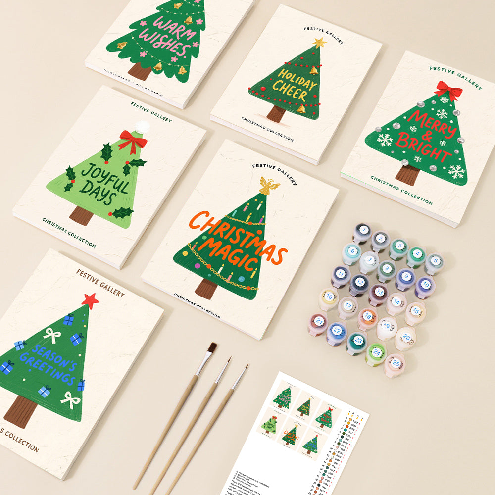 A festive flat lay displays multiple paint by number canvases featuring cheerful, stylized Christmas tree designs with holiday greetings, accompanied by numbered paints and brushes.