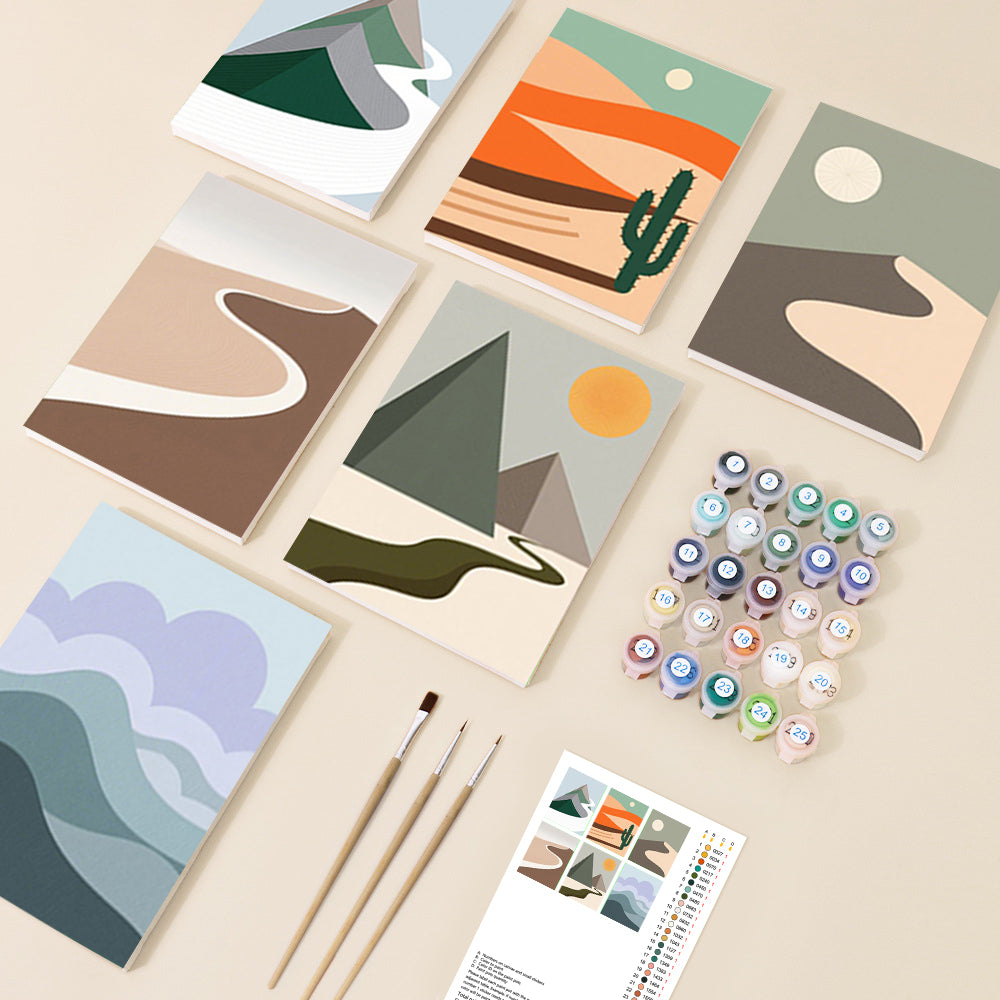 An overhead view of a minimalist landscape collection, featuring several abstract nature scenes with mountains, deserts, and clouds, accompanied by paint pots and brushes in a modern, serene style.