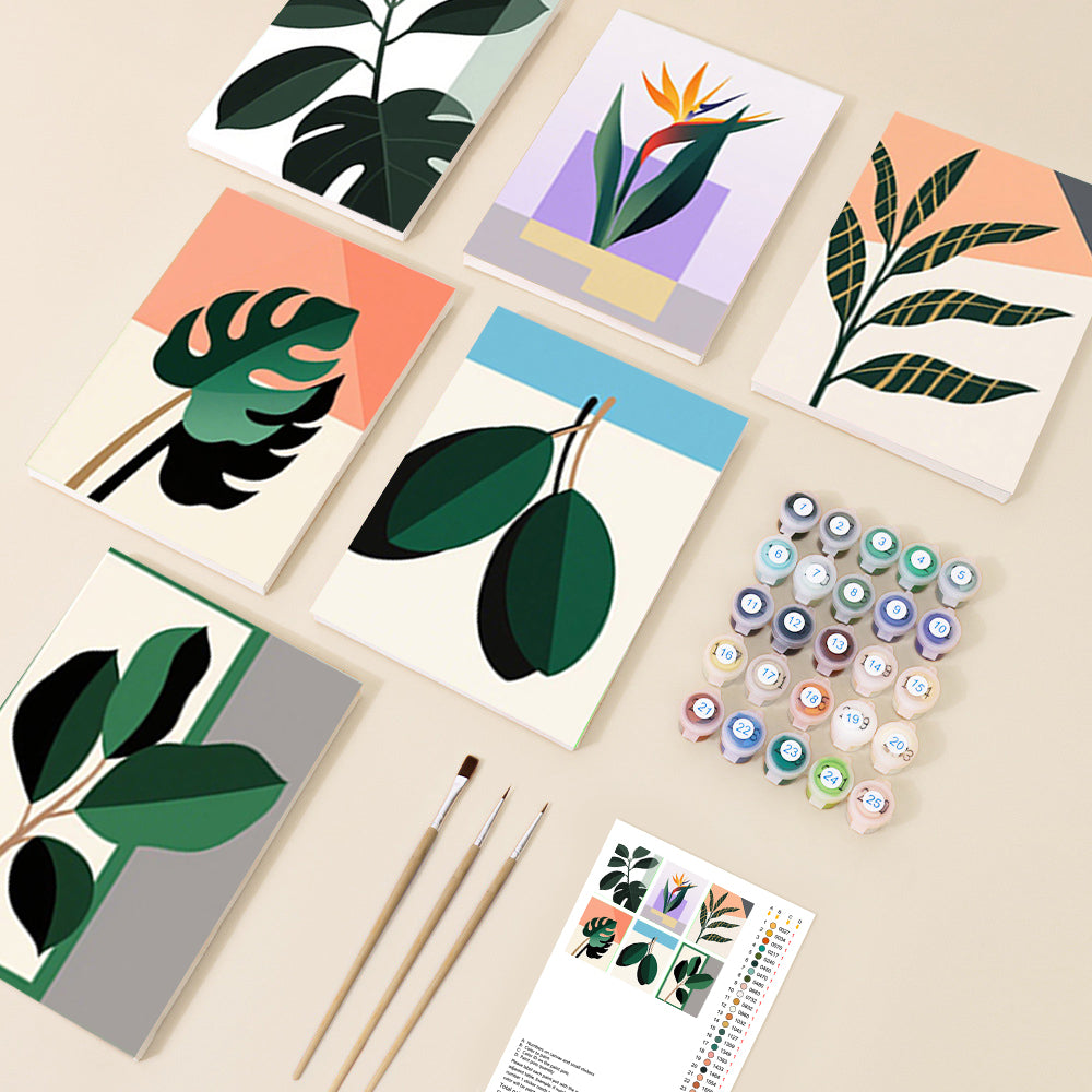 An overhead view of several small canvases featuring modern, abstract botanical designs of various leaves and a bird of paradise flower, surrounded by paint pots and brushes.
