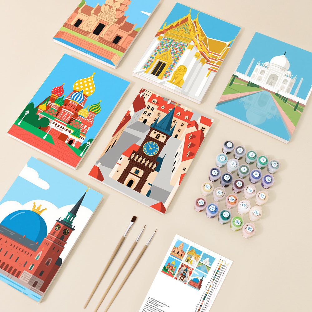 An overhead view of paint by number canvases showcasing simplified, colourful illustrations of six famous world landmarks including the Taj Mahal and St. Basil's Cathedral, alongside paint pots and brushes.