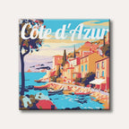 A vibrant, retro-style illustration depicting a picturesque Côte d'Azur coastal village with colourful buildings, boats in the sea, and the text 'Côte d'Azur' across the sky.